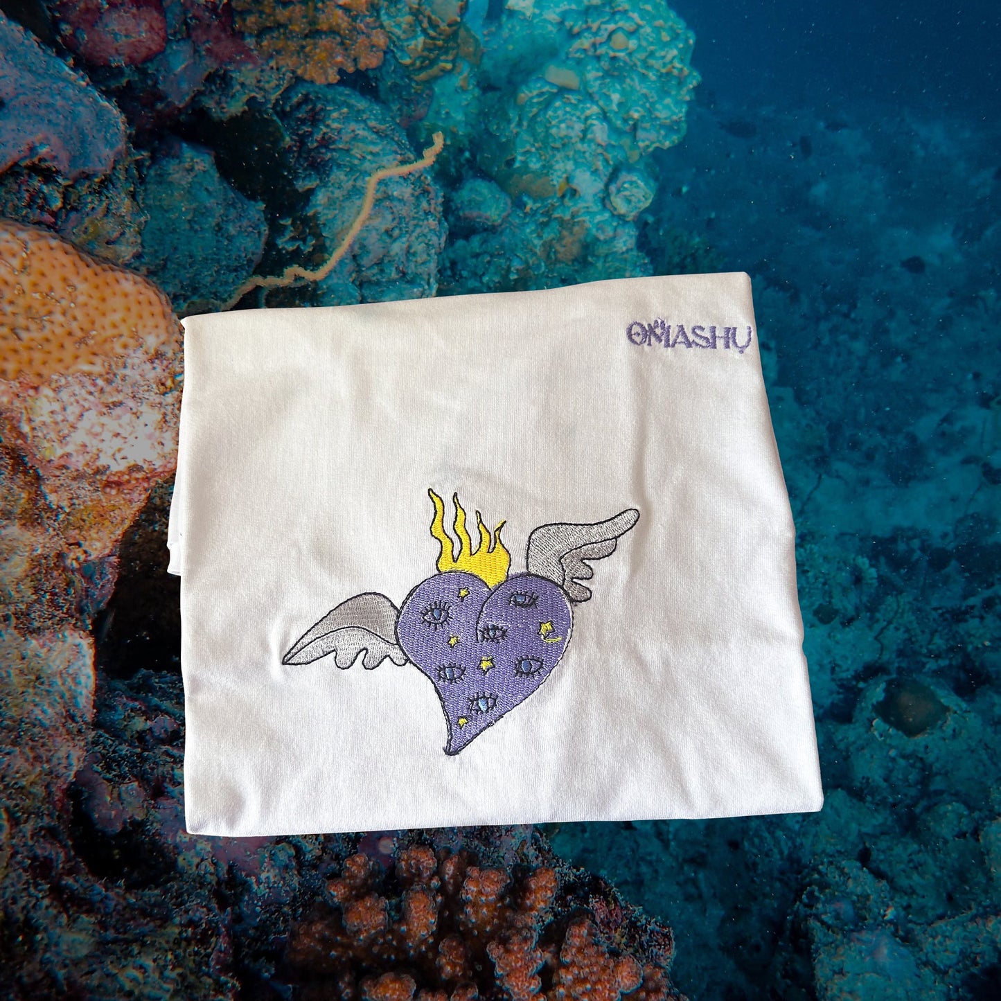 a folded t-shirt with purple heart and brand name Omashu