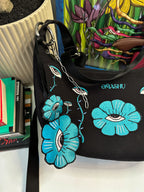 a bag and key chain both has embroidered illustration, it also has OMASHU branding on it. on the back ground there is a pot and books