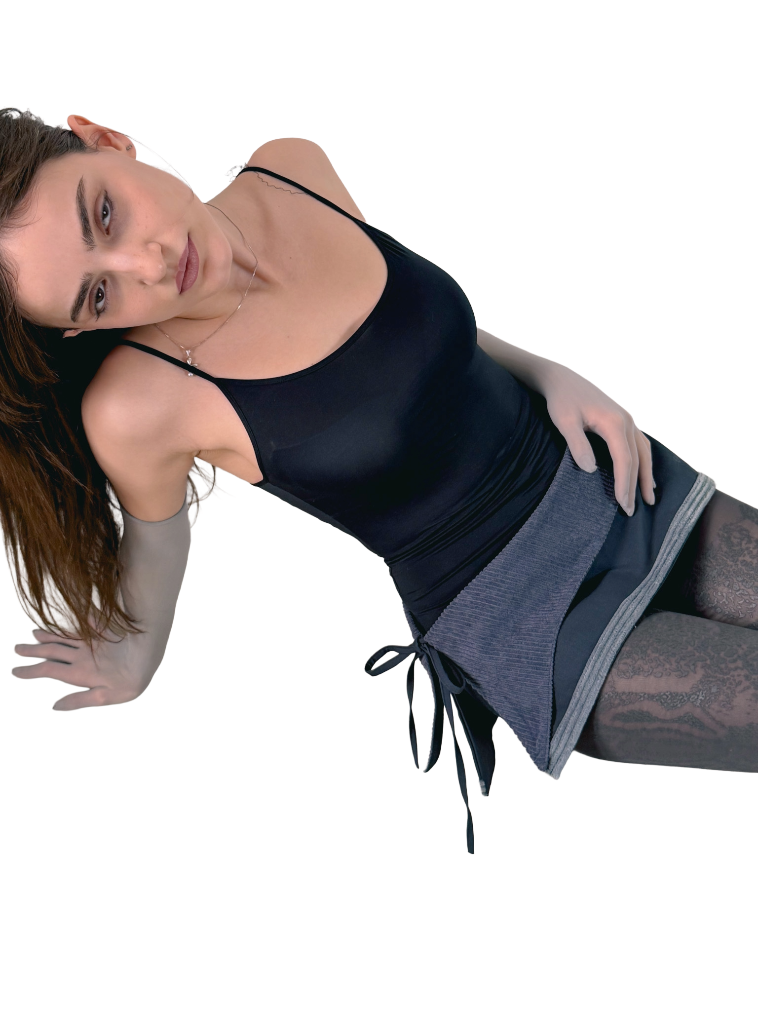 Woman wearing a black tank top and gray skirt on a white background