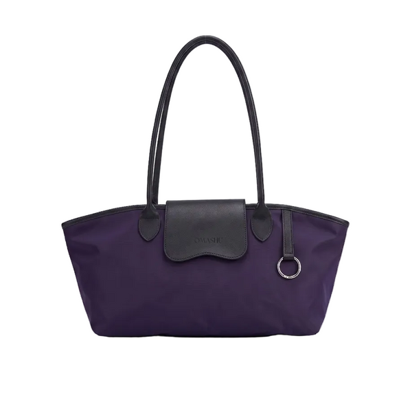 A purple nylon tote bag with black leather handles, trim, and a front flap pocket, shown against a light gray studio background.