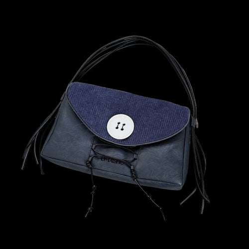 Blue handbag with black fringes on a concrete floor