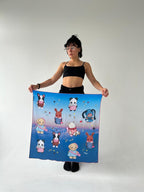 Model posing with a large silk scarf adorned with cute animal characters like a dog, panda, and rabbit, set against a sky-themed background. A fun and stylish accessory, great for those who enjoy animal-themed fashion or handmade scarves.