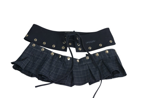 Omashu AYA Belted Layered Skirt featuring a dark, textured pleated mini skirt with silver-tone snap buttons and an attached wide black corset-style belt with front lacing and eyelets.