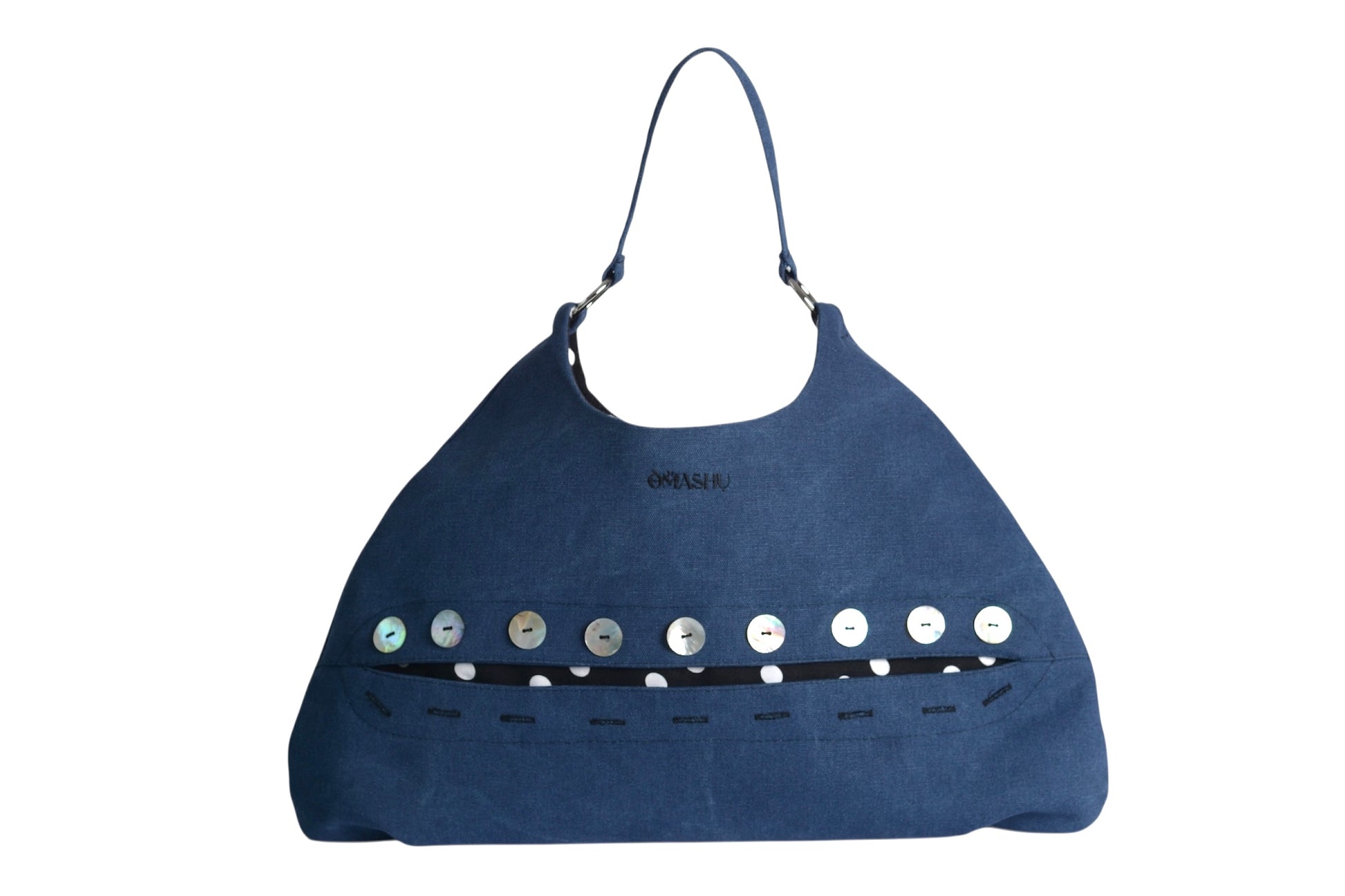 Front view of the Omashu Sylvie Eclipse Bag in blue fabric with its signature button-down 'eclipse' detail showcasing a black and white polka dot interior accent.