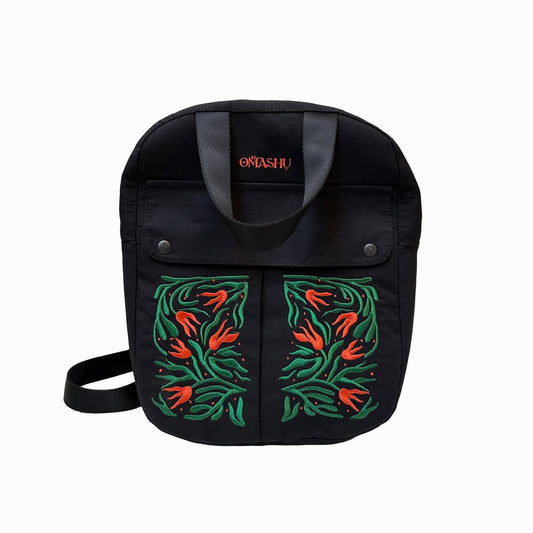 A black OMASHUshoulder bag with a colorful floral design on the front and a red brand name on the handle