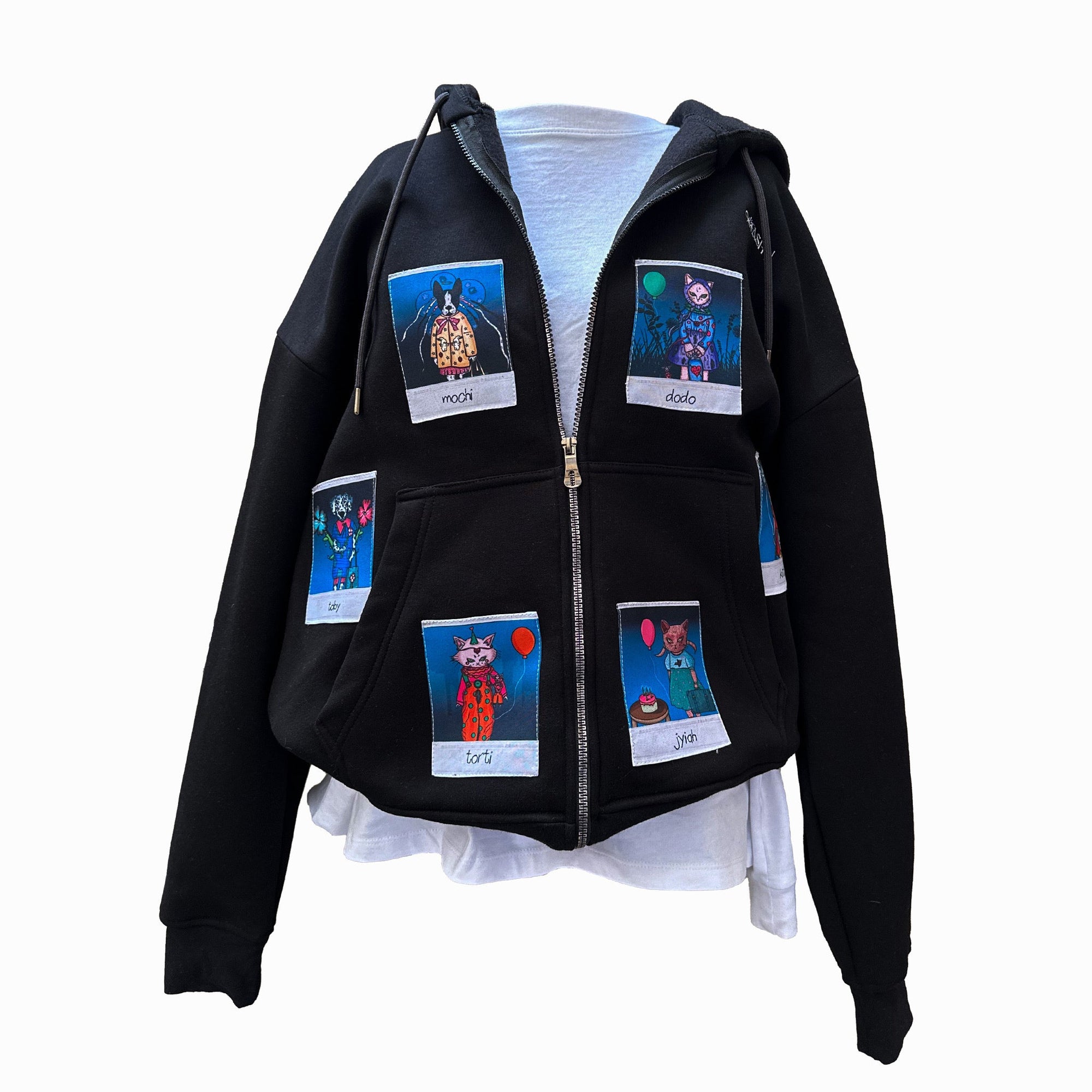 A black zip-up hoodie displayed on a mannequin, featuring six colorful Polaroid-style patches of animal characters. The characters include "Mochi," "Dodo," "Torti," "Jiyah," "Toby," and another on the back. The hoodie is shown with the zipper open, revealing a white inner layer underneath.