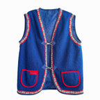 Blue vest with red and white trim, two pockets on front with red trim, hook and eye closure at front, and label on inside that reads ‘OMASHU’.