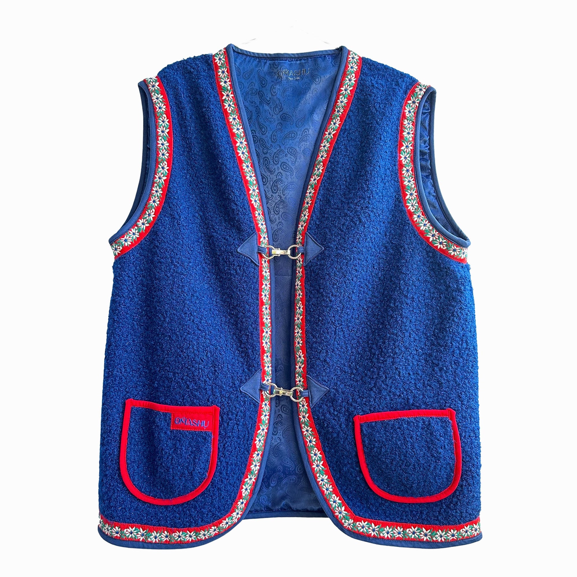 Blue vest with red and white trim, two pockets on front with red trim, hook and eye closure at front, and label on inside that reads ‘OMASHU’.