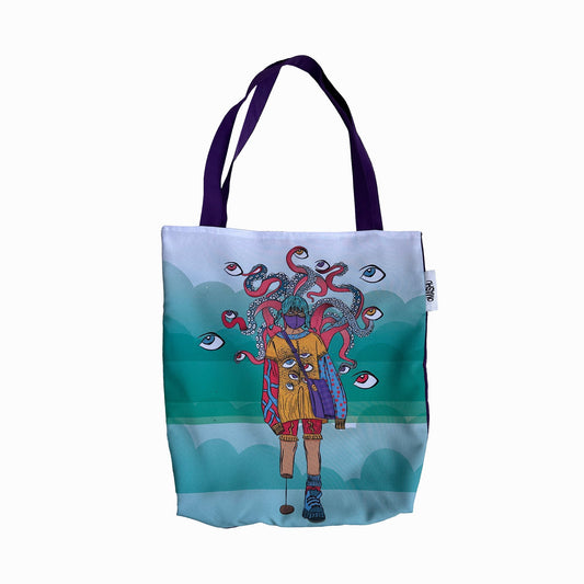 A tote bag with a colorful design on it. The design is of a person with an octopus on their head, standing on a beach with fish in the background. The person is wearing a yellow dress with blue stripes and blue shoes. The octopus is pink and purple with tentacles that are curling around the person’s head. The background is a light blue with fish and waves. The tote bag has purple handles and a white tag on the side.